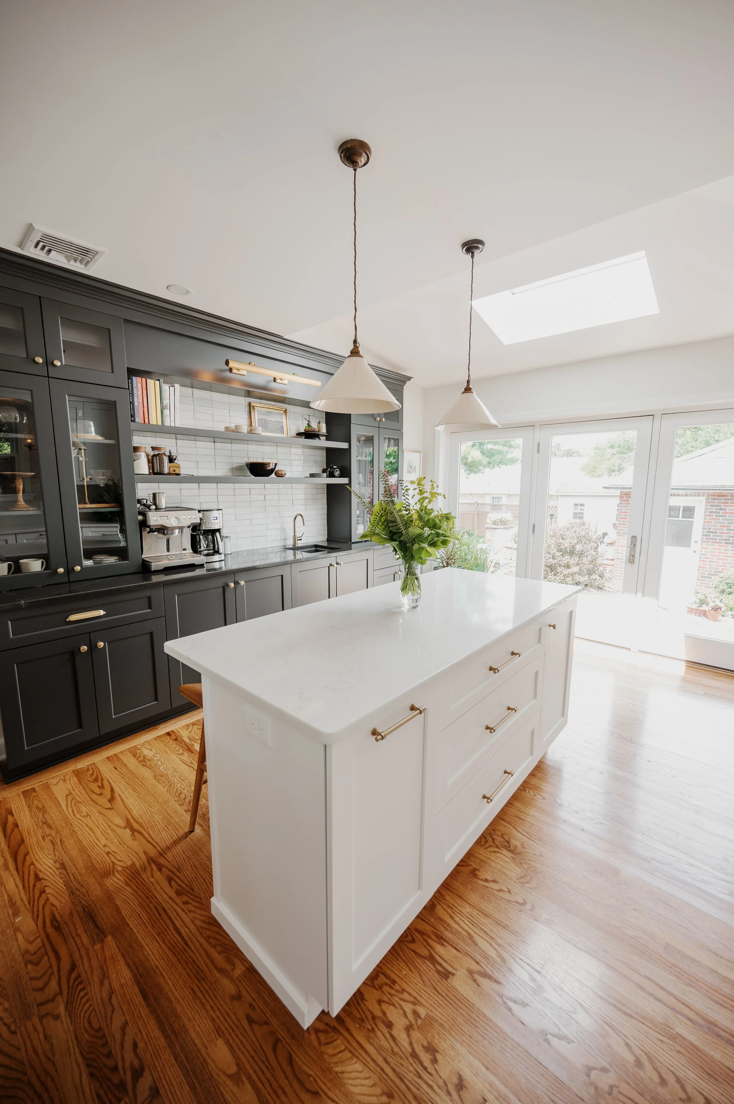 Renovated kitchen with dark cabinetry, white island and custom storage designed by FD Design Co.