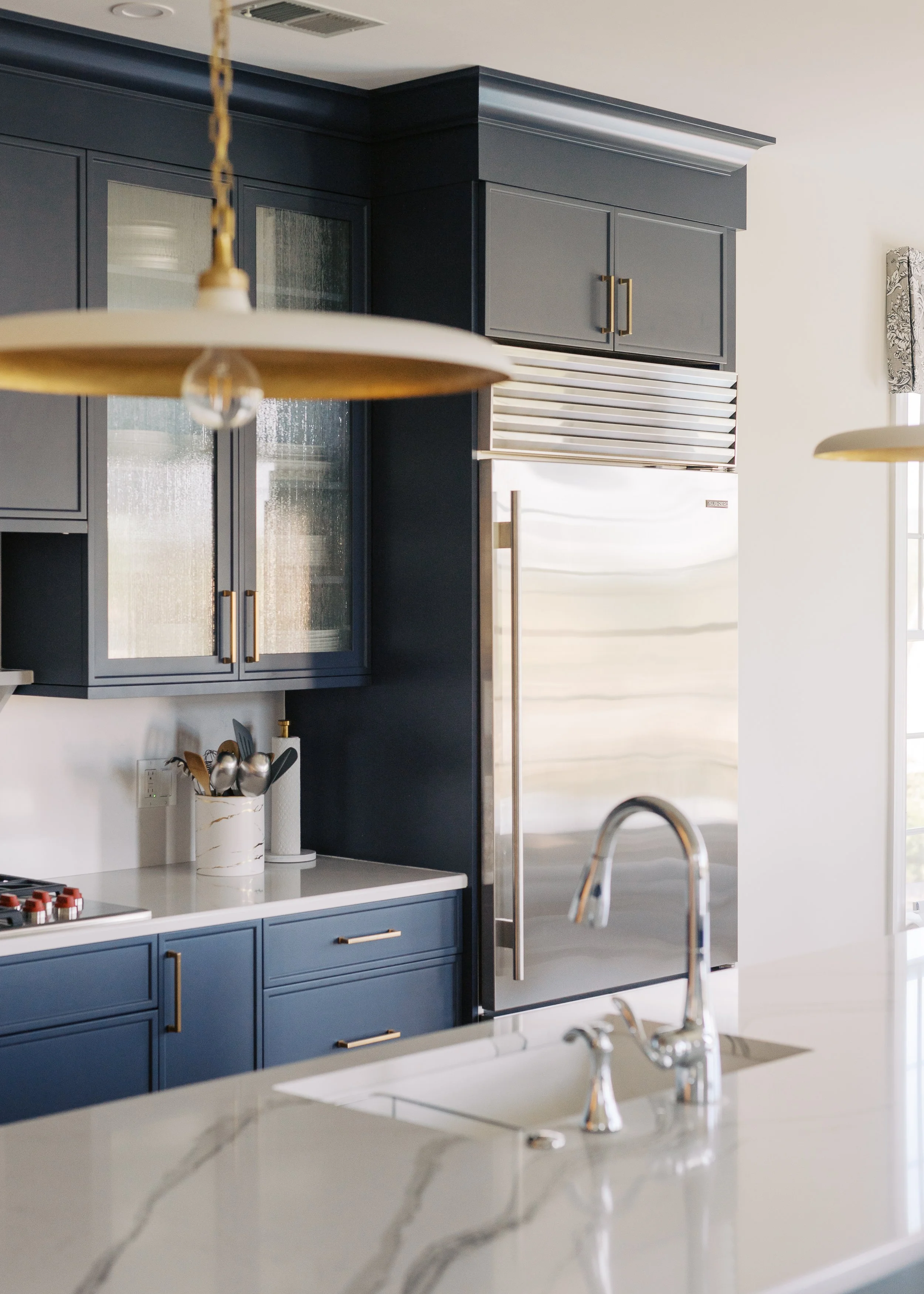 Custom kitchen with dark cabinetry, integrated storage and white countertops designed by FD Design Co.