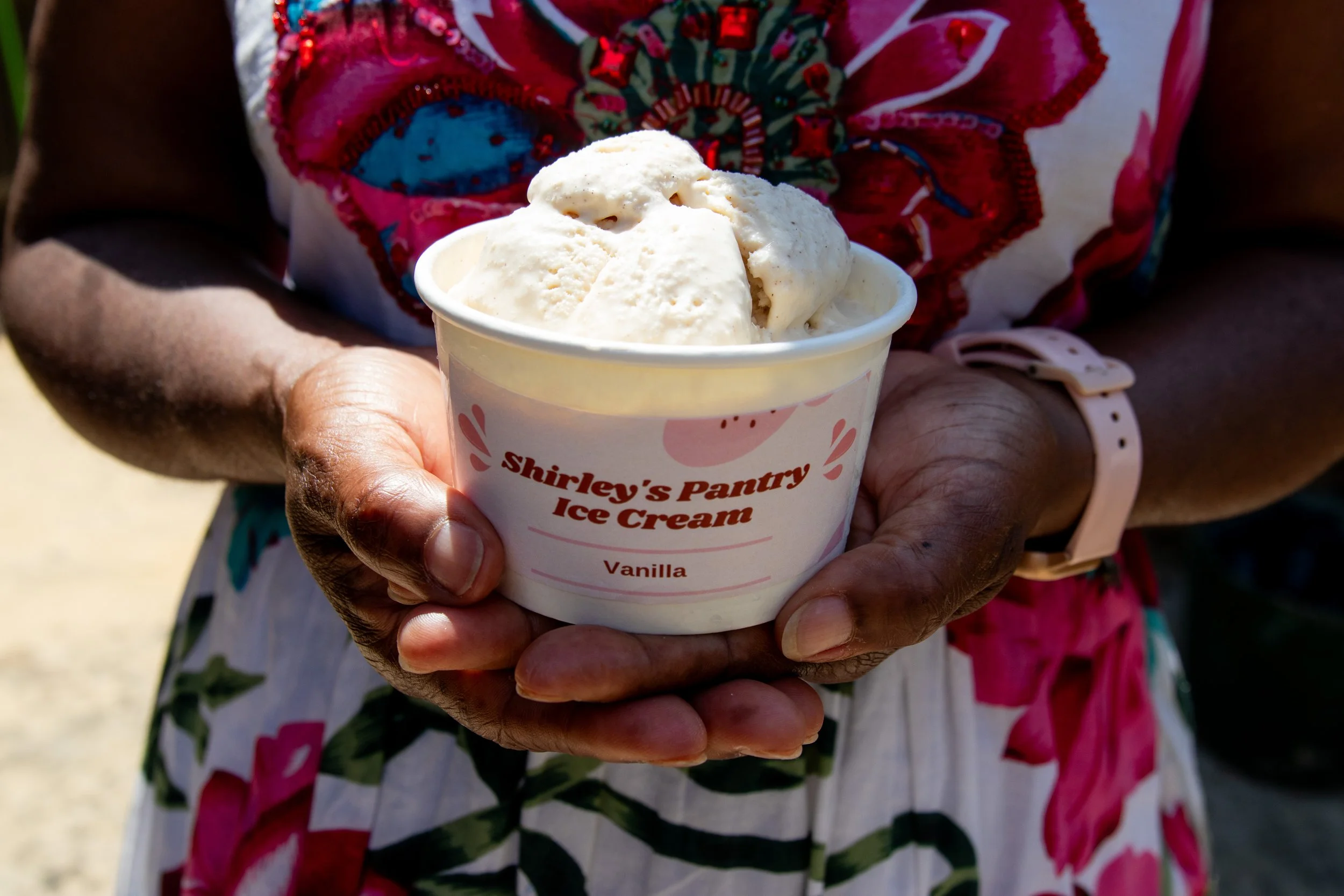 Hand overlapped holding Shirley's Pantry Vanilla flavoured ice cream container