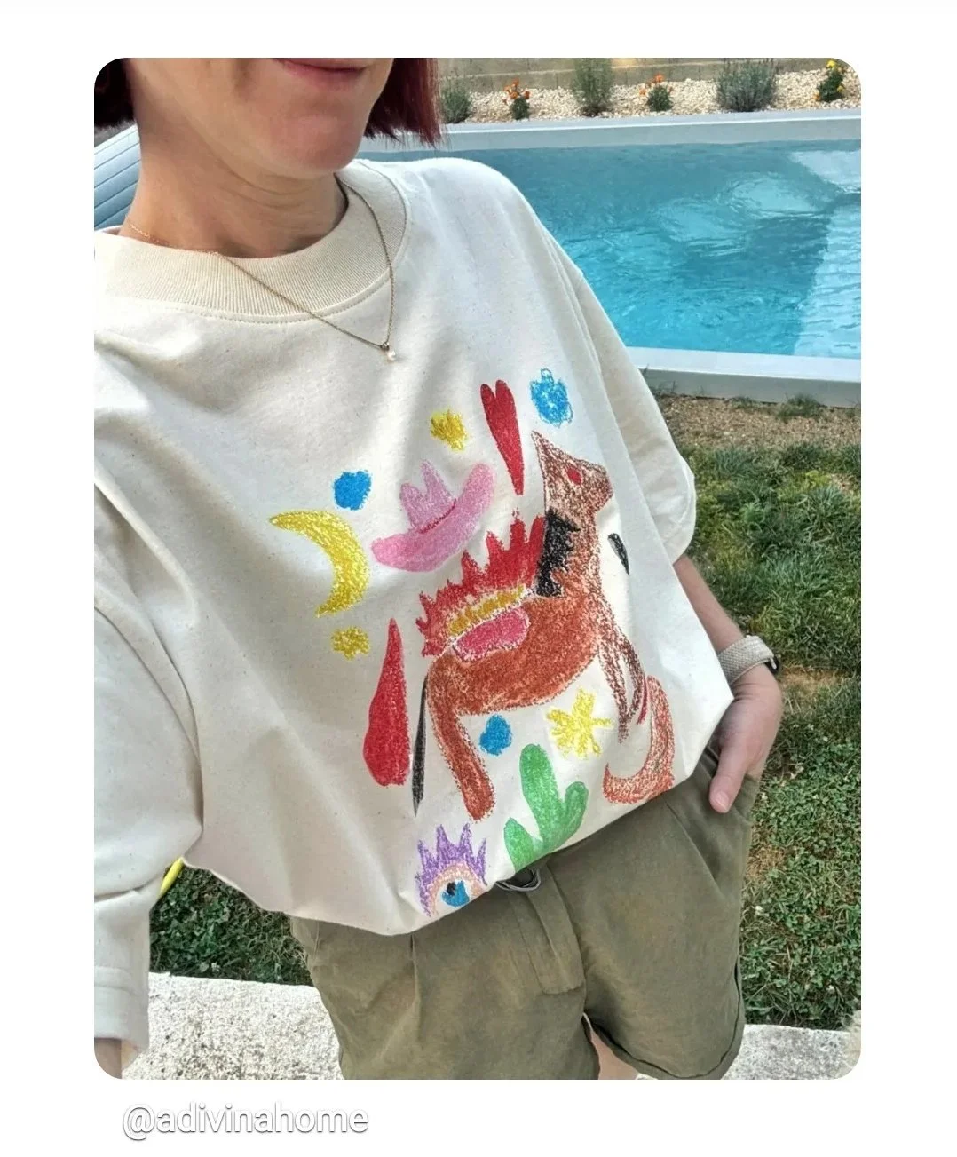 Personne portant un T-shirt avec une peinture colorée représentant un cheval, près d'une piscine extérieure.