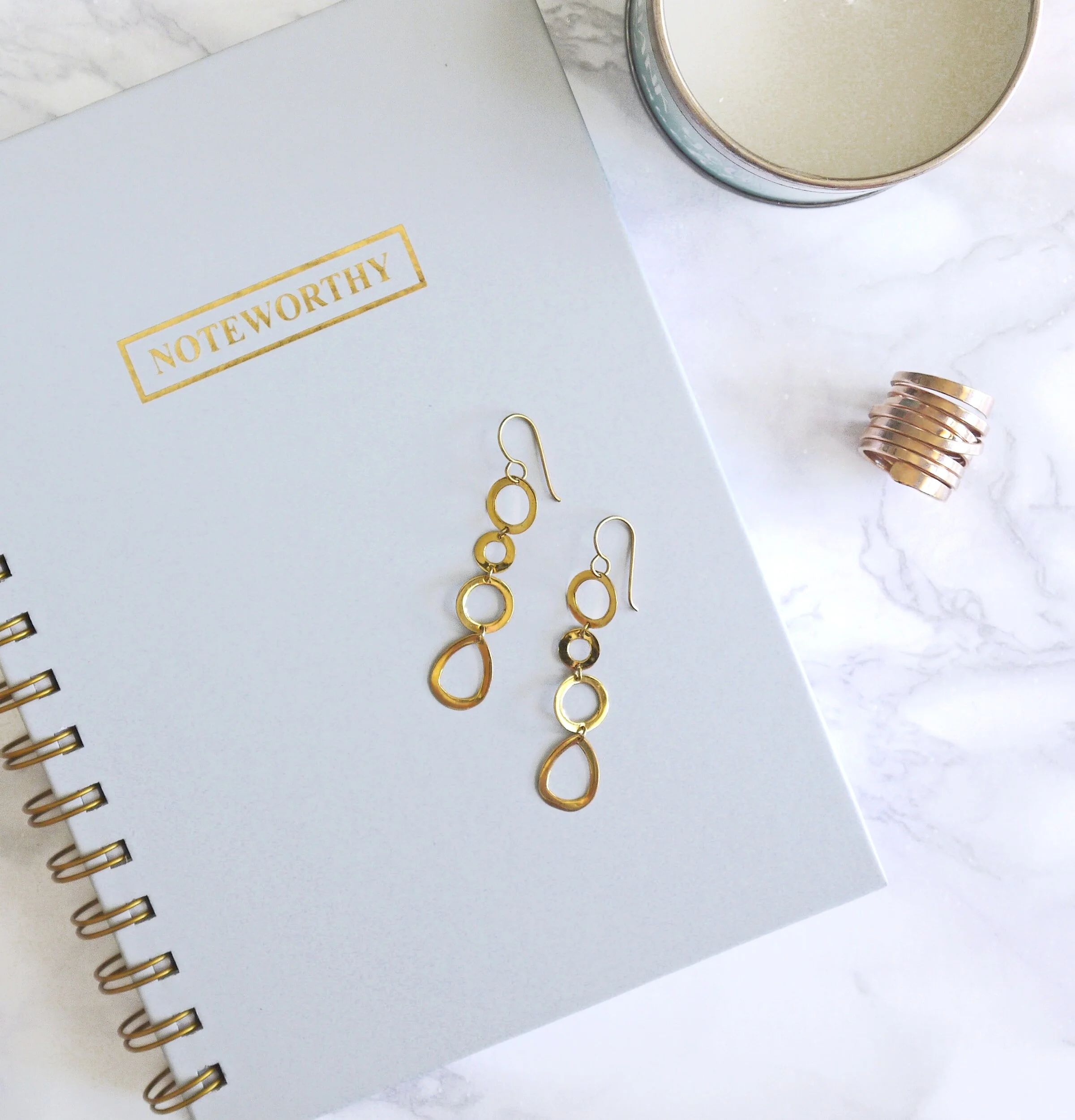 Gold earrings sitting on top of a notebook