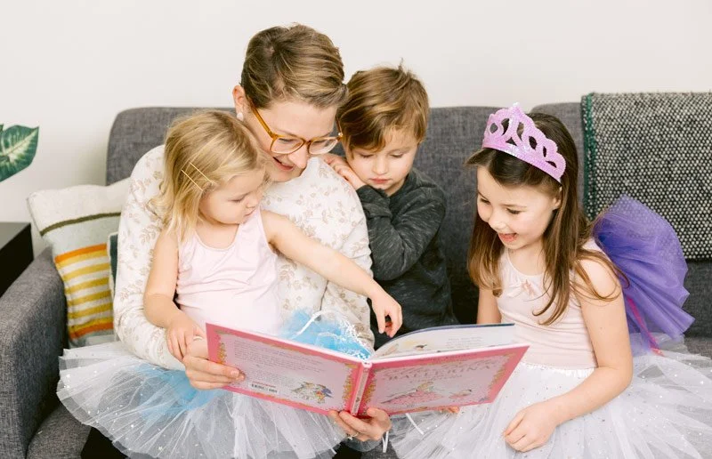 Mom reading ballet book to girl dressed in tutu