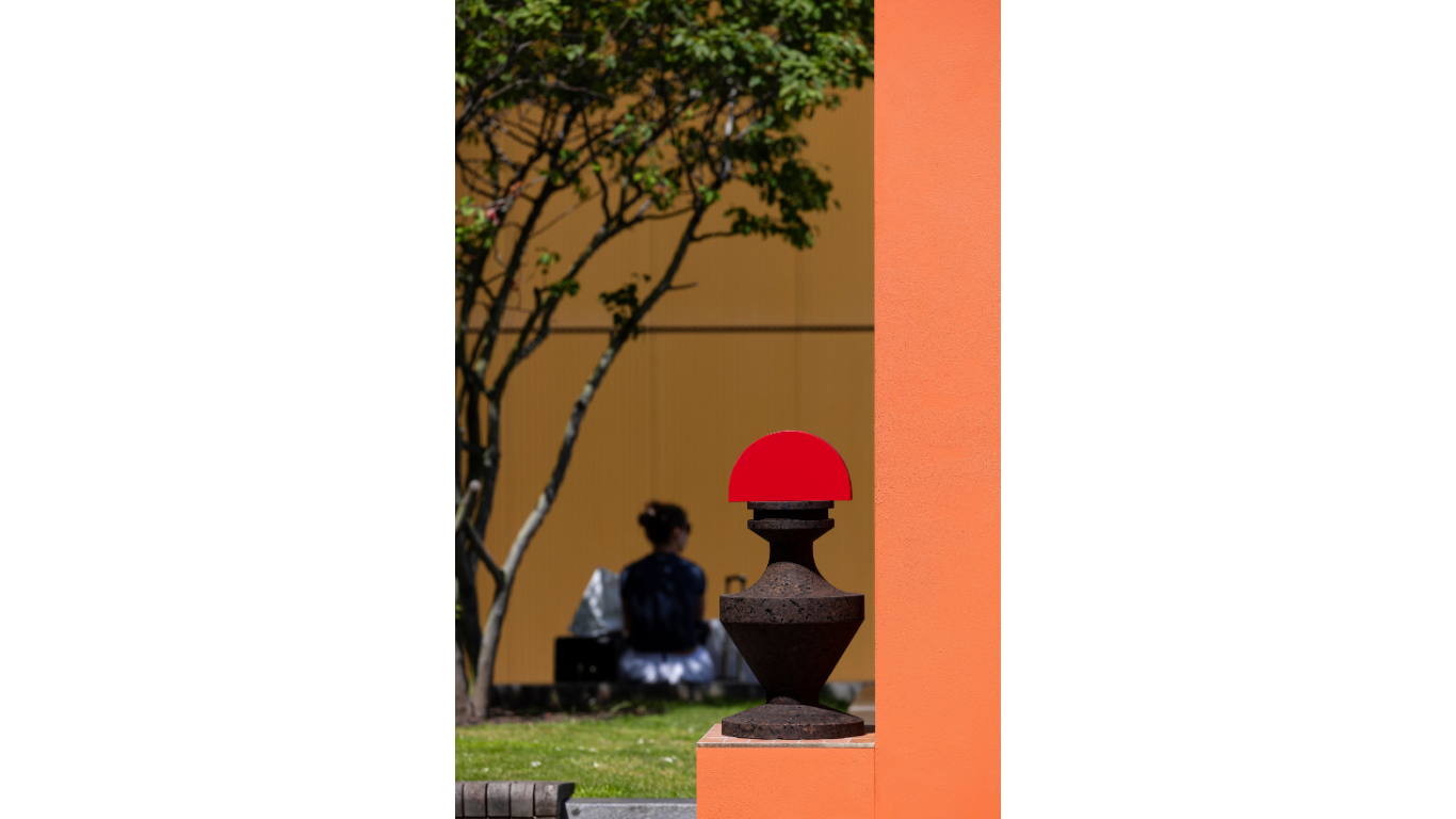 An image of a cork sculpture resting upon a tiled step designed into the large outdoor installation by Simone Brewster. In the background is a woman sitting nearby.