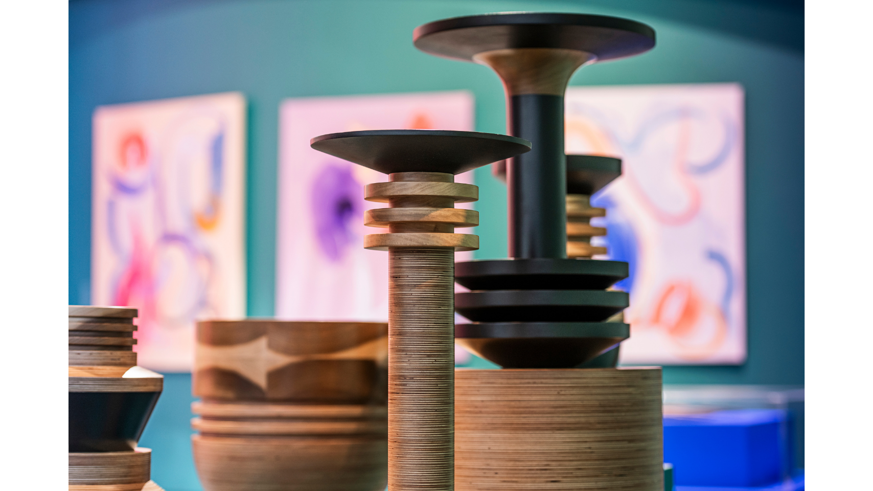 A close up of the top of the Tropical Noire sculptural vessels. Blurred out in the background are three colourful paintings lined up in a row on a turquoise coloured wall