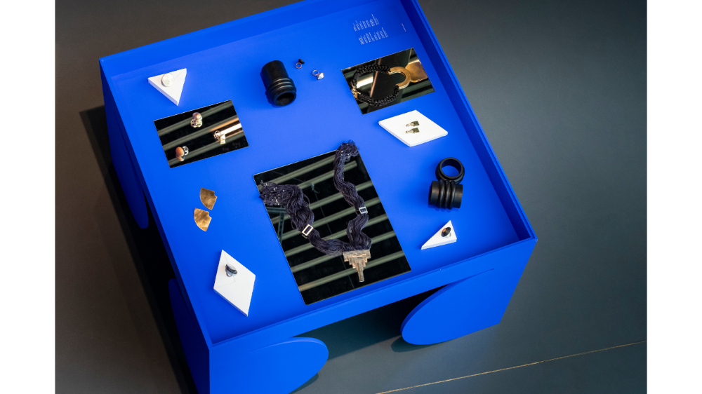 A birds-eye photograph of the Klein blue table designed by Simone Brewster displaying jewellery, including the Metropolis Skyscraper Necklace as well as braclets from the Ebony Revolution collection.  