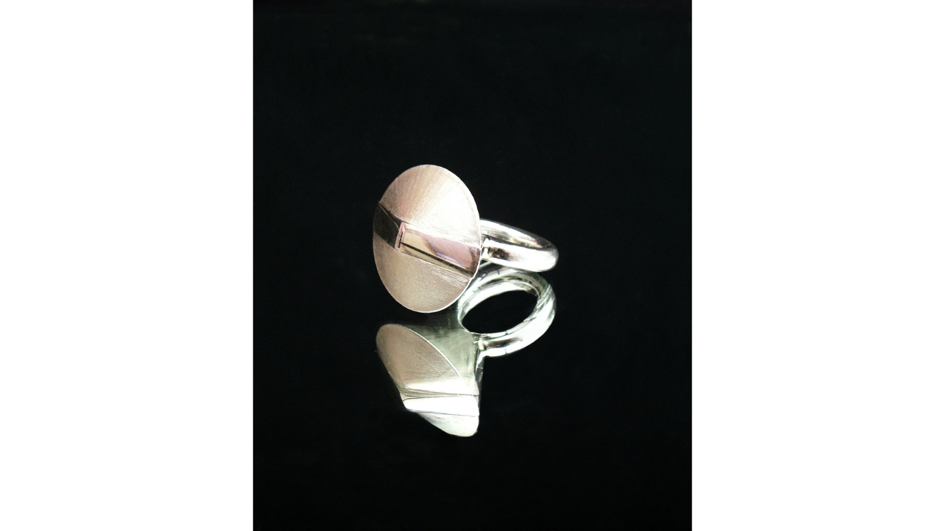 Close up of silver ring with a smooth round circular surface designed by Simone Brewster 
