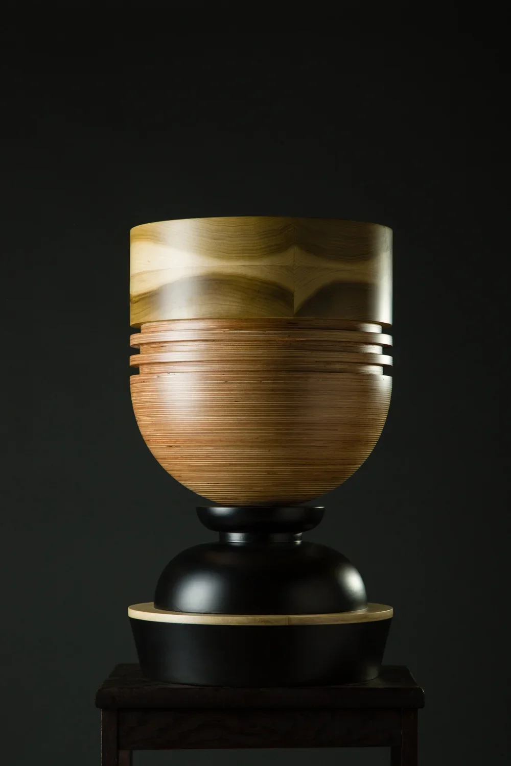 A sculptural vessel that forms a part of the Tropical Noire collection by artist, Simone Brewster. The sculpture is made of carved timber wood, drawing on African cereminal forms. Hand-crafred wood sculpture.