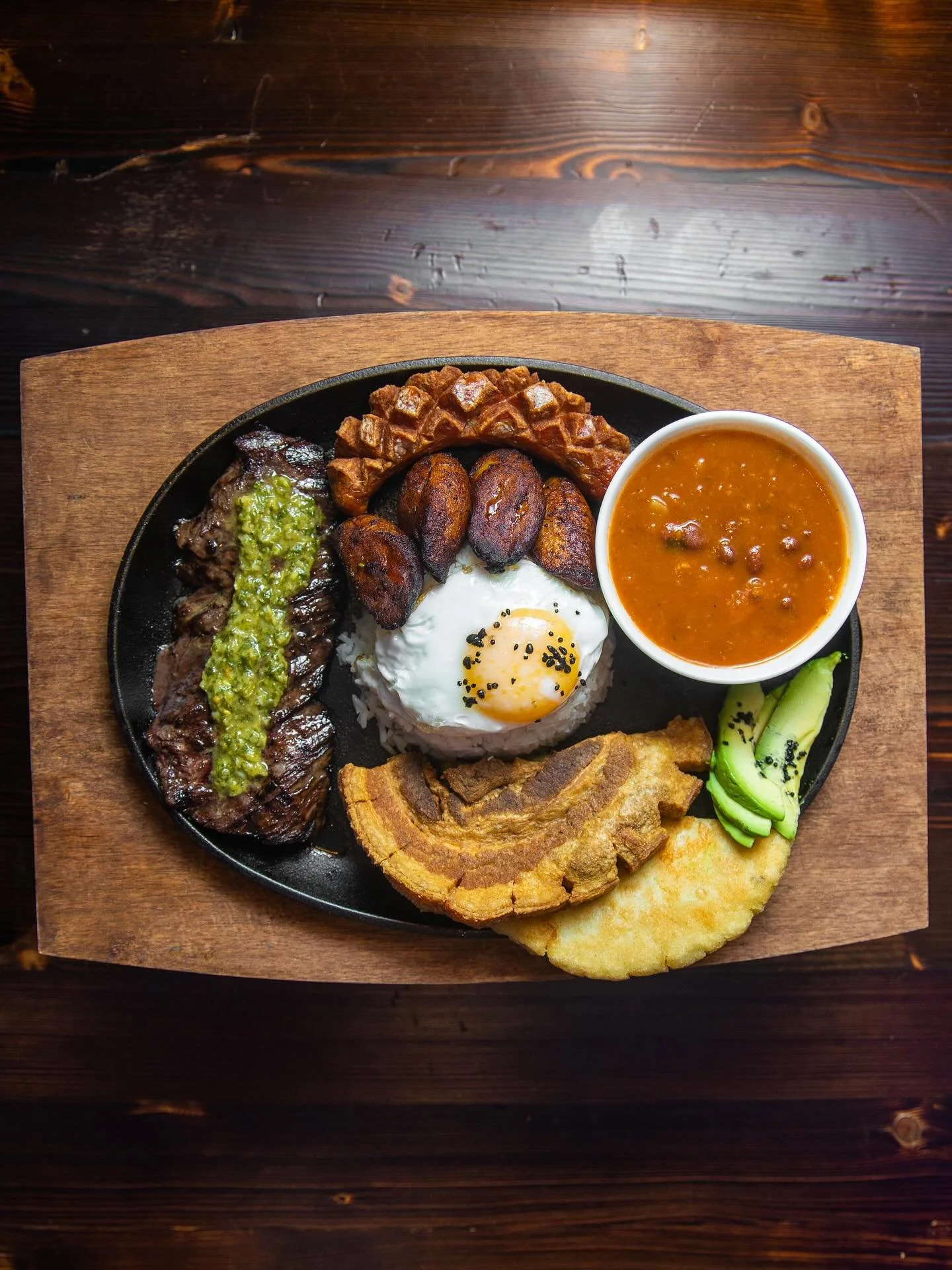A true Colombian classic, ELEVATED. Our Bandeja Paisa brings rich, soulful flavors &mdash; grilled meats, creamy beans, maduros and a perfectly fried egg &mdash; all served with heart and heritage. ✨ #PuertasRestaurant #BandejaPaisa #LatinSoul #Colom