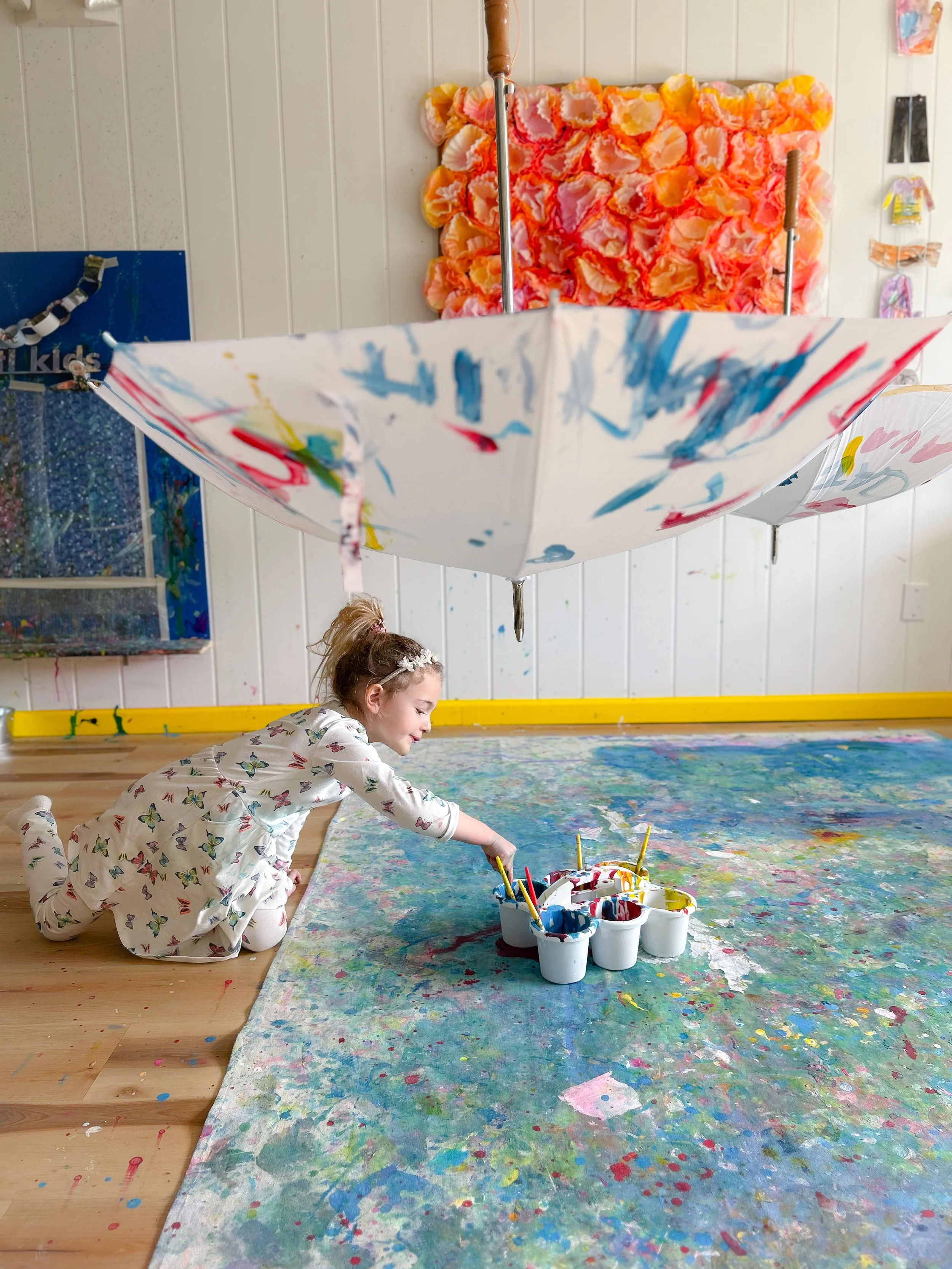 preschooler painting with yogurt paint on giant canvas