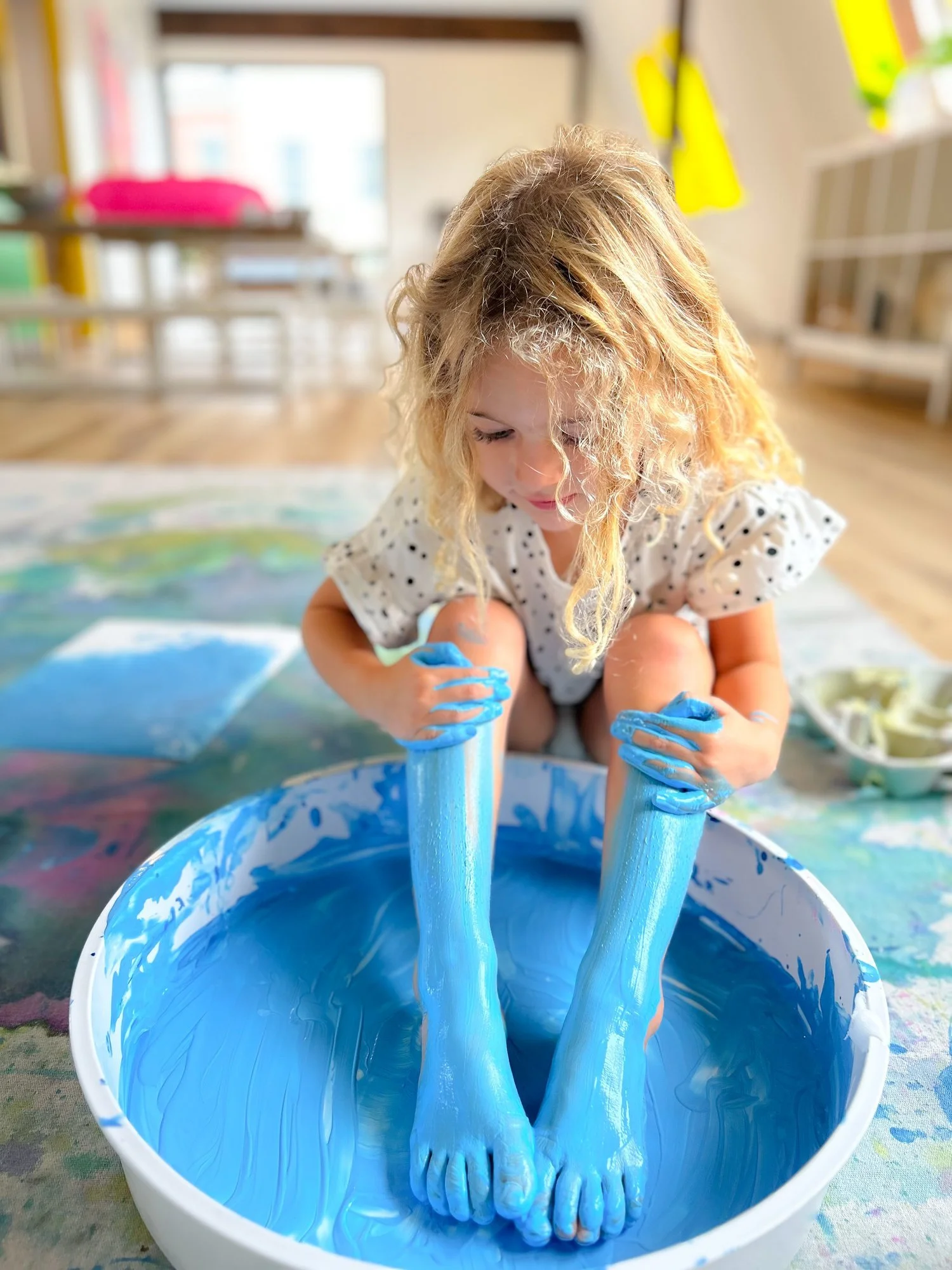 toddler sitting in pain tub of blue paint