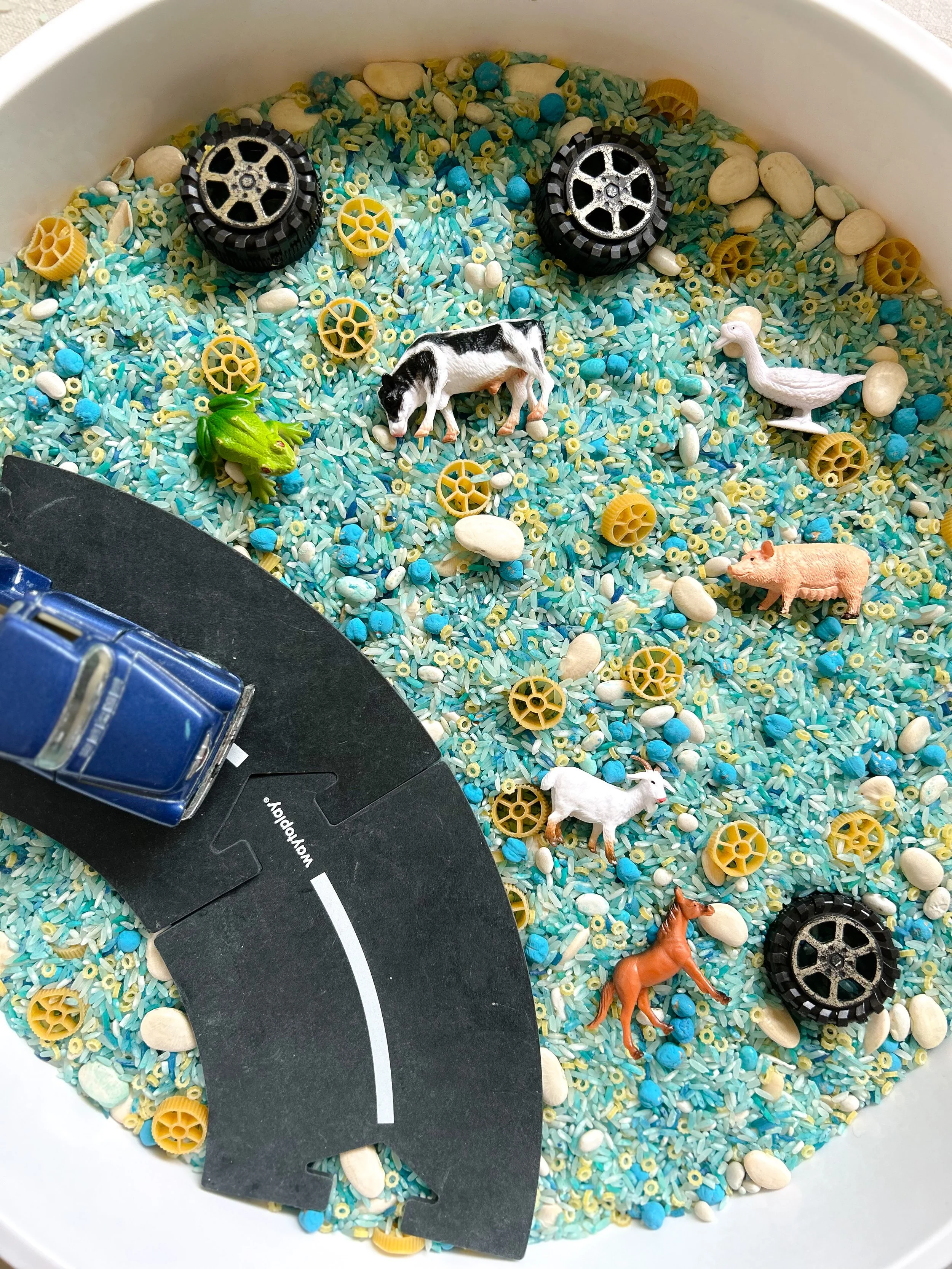 rice sensory bin with farm animals and trucks