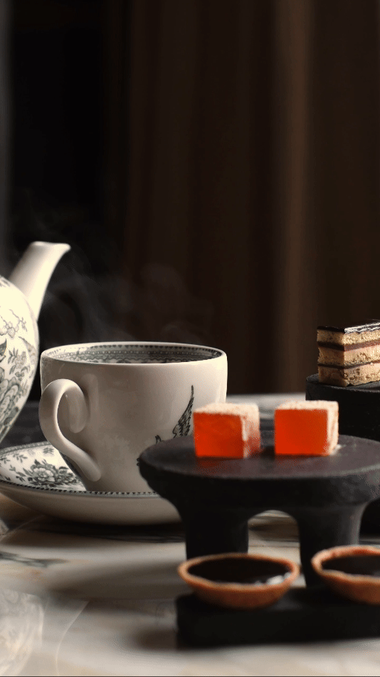 Krus, teiprose, små kaker og tekopper på et bord.