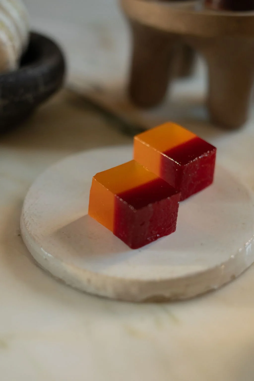 To firkantede gele- og røde geléer på en hvit plate.