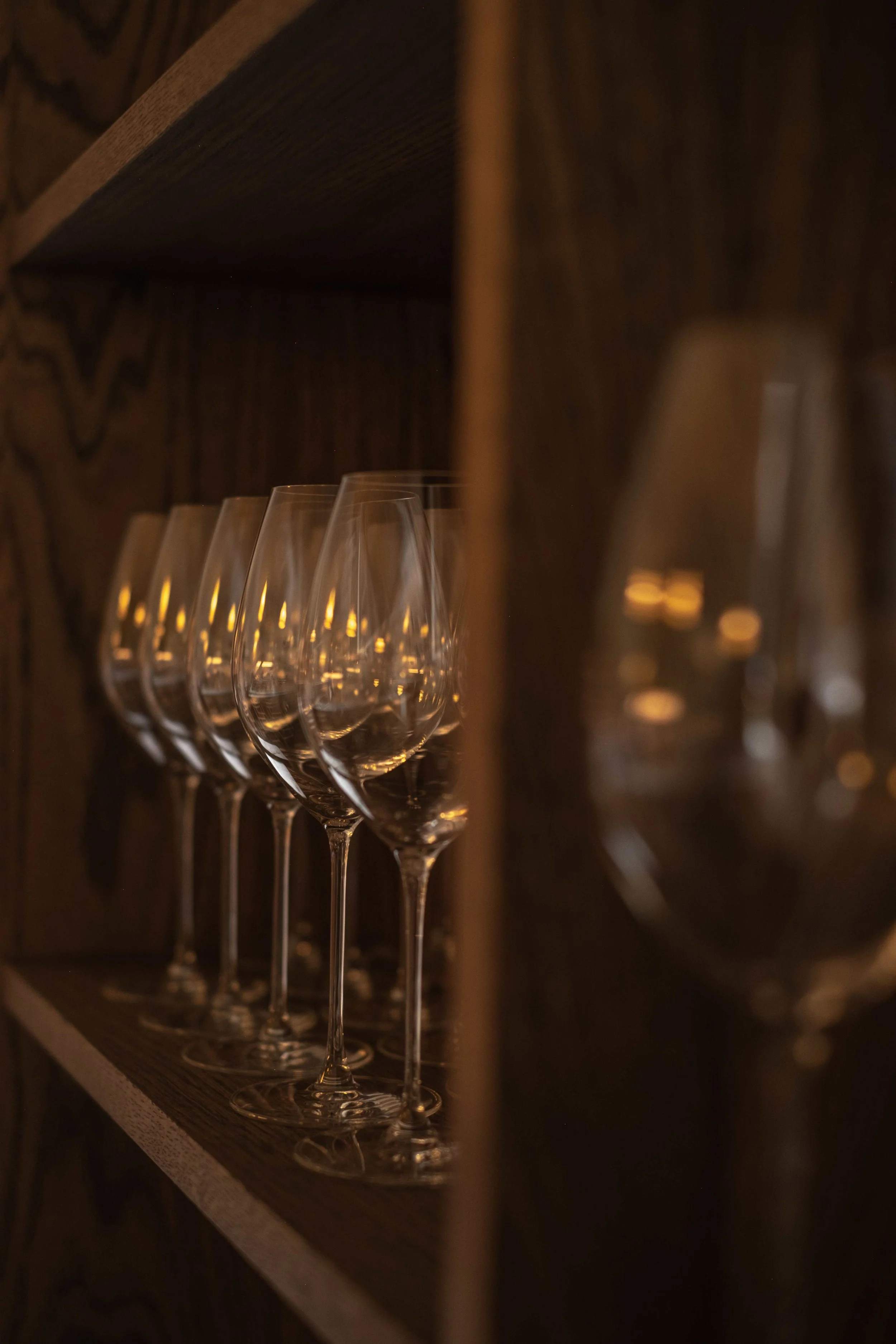 Fem tomme champagne-glass på rekke på en trehylle.