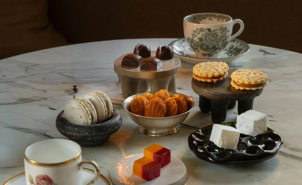 Kaffeekopp, diverse kaker og sjokolade på en marmorbord.