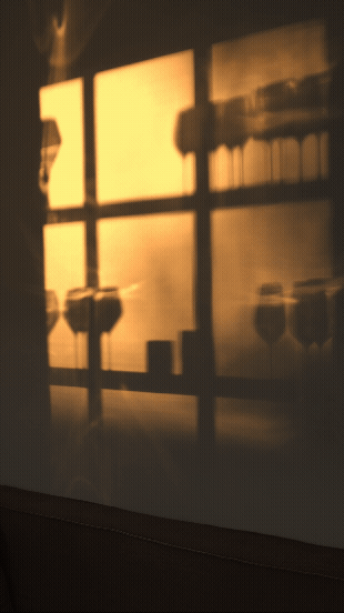 Solskinn som skinner gjennom et vindu, og skaper skygger av hyller med krukker