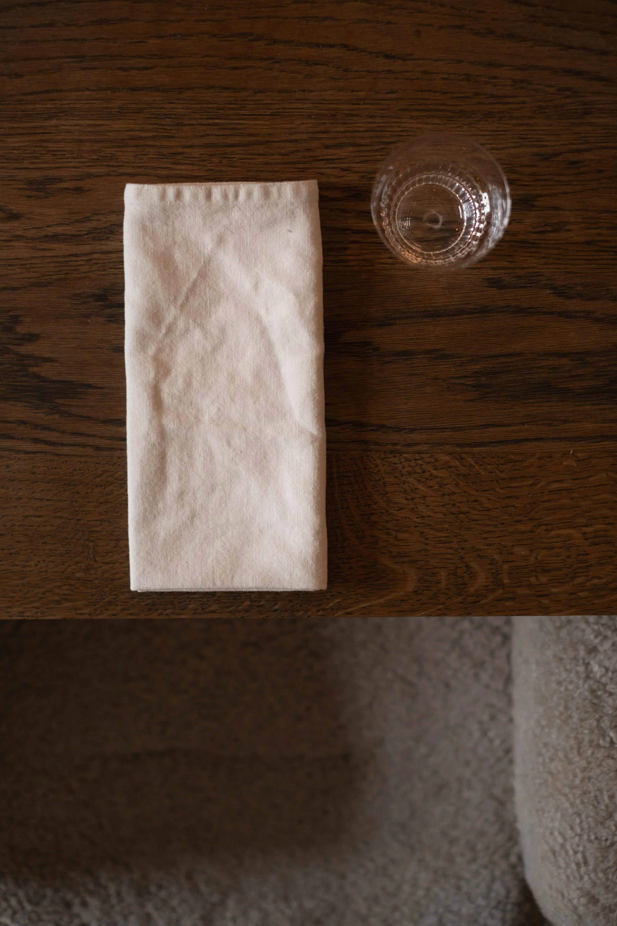Et krøllet papirserviett og et vann glass plassert på en trebord.