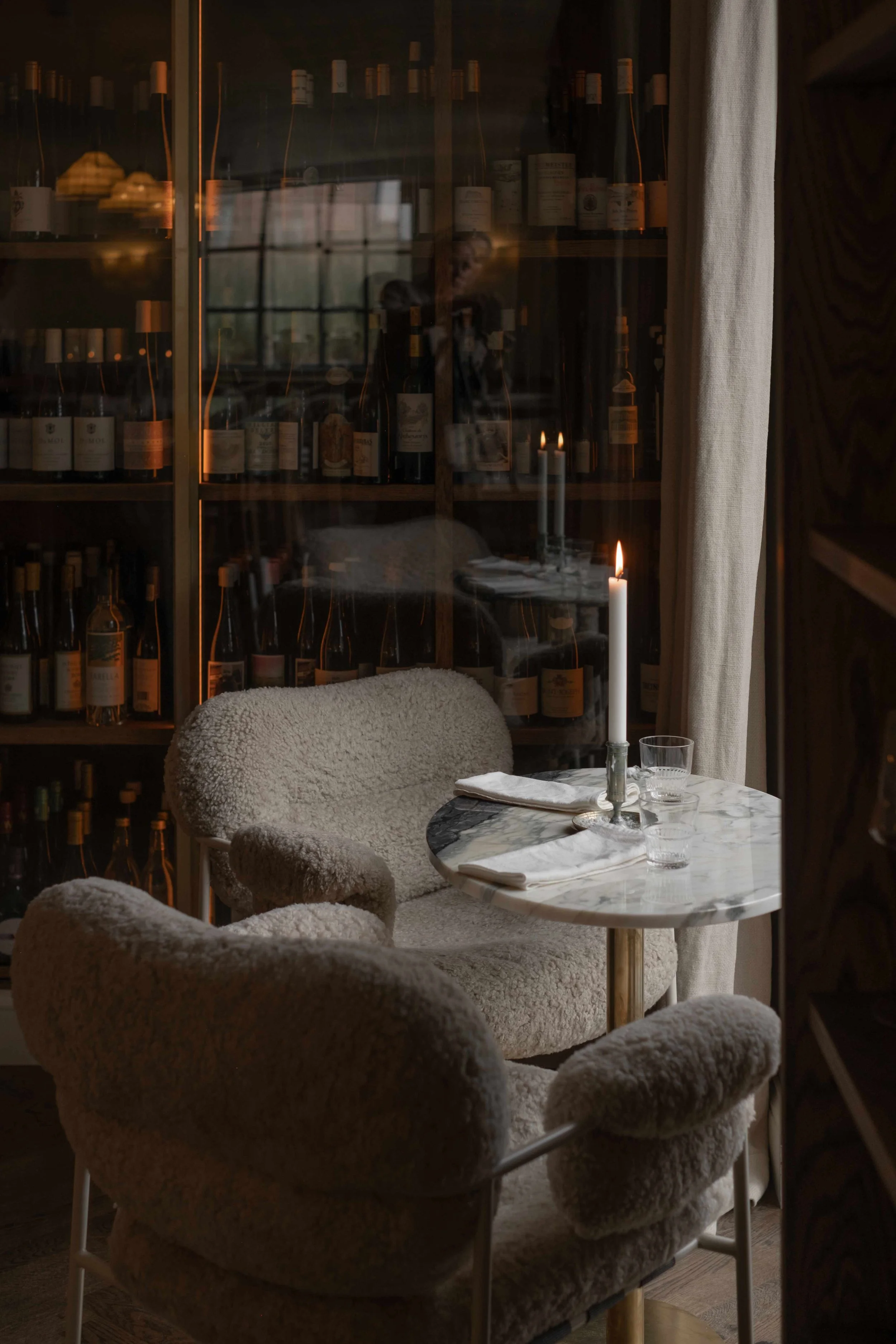 Et koselig spisehjørne med to stoler og et lite bord med lysende lysestaker, omkranset av en vinmur og ihvertfall en duk.