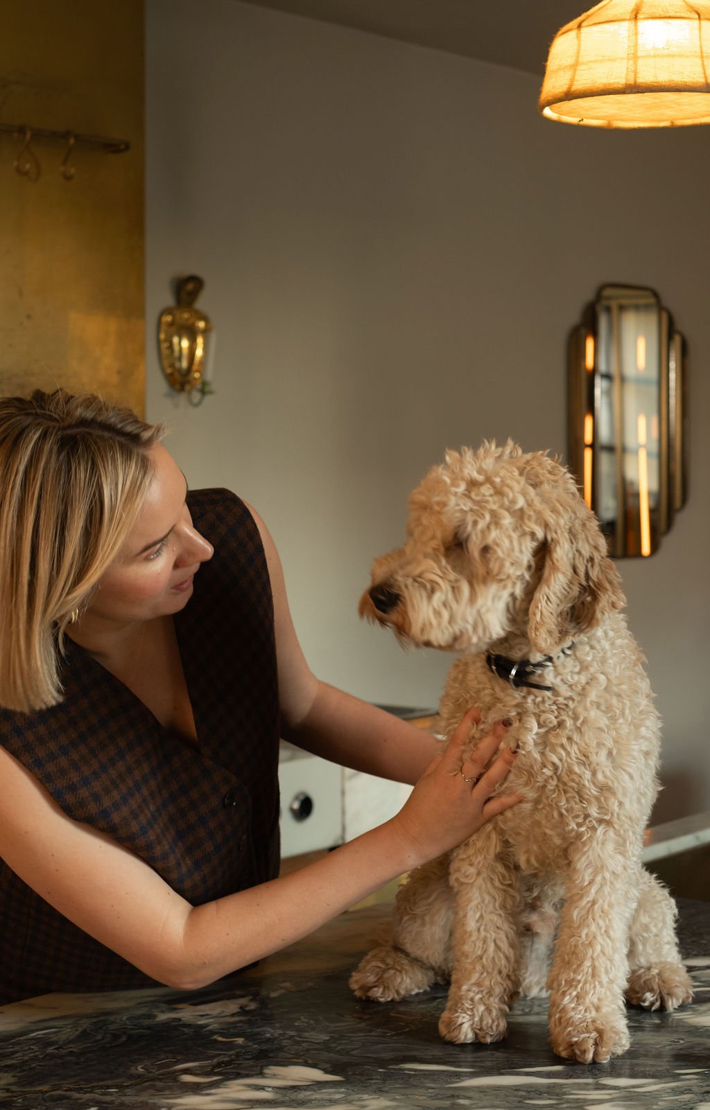 En kvinne med blond hår som leker med en godstispe i et rom med varme lamper og speil.