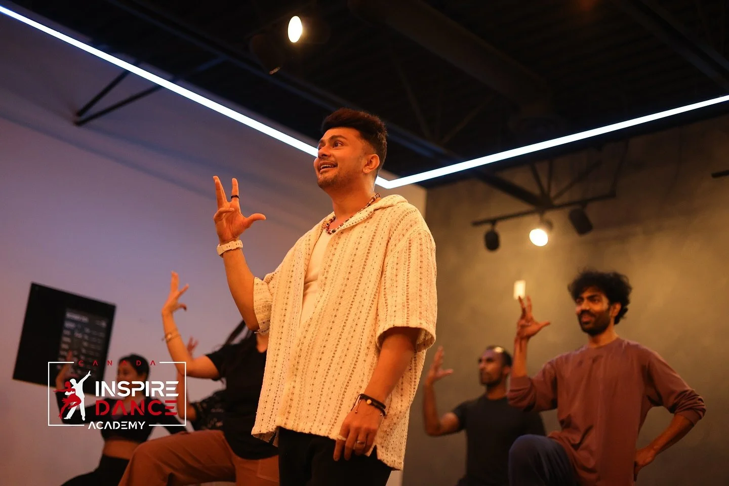 Dance instructor leading a class at Inspire Dance Academy with three students in a dance studio with modern lighting.