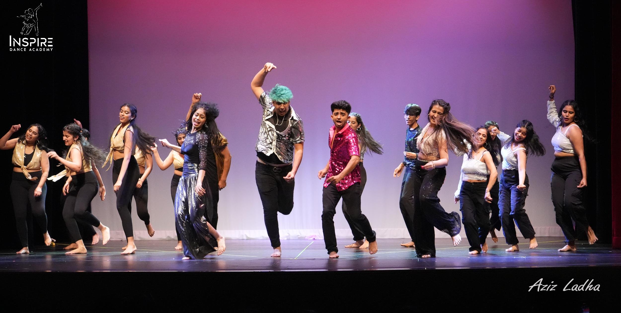 Group of young dancers performing on stage at Inspire Dance Academy, with vibrant outfits and energetic movements.