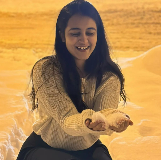 Woman smiling and holding a slice of cake, with a snowy background.