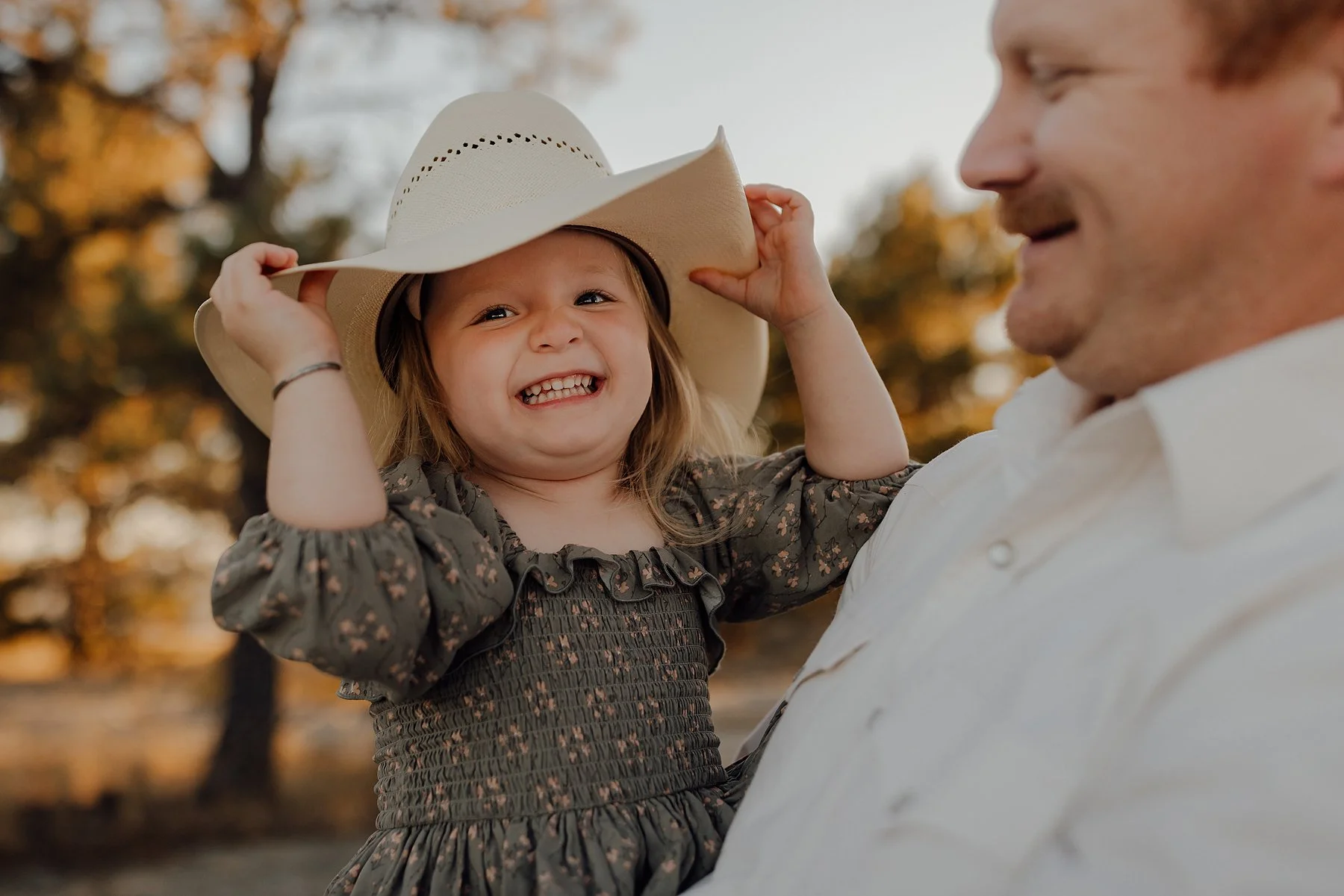A family of six sharing a kiss and holding hands outdoors during sunset.