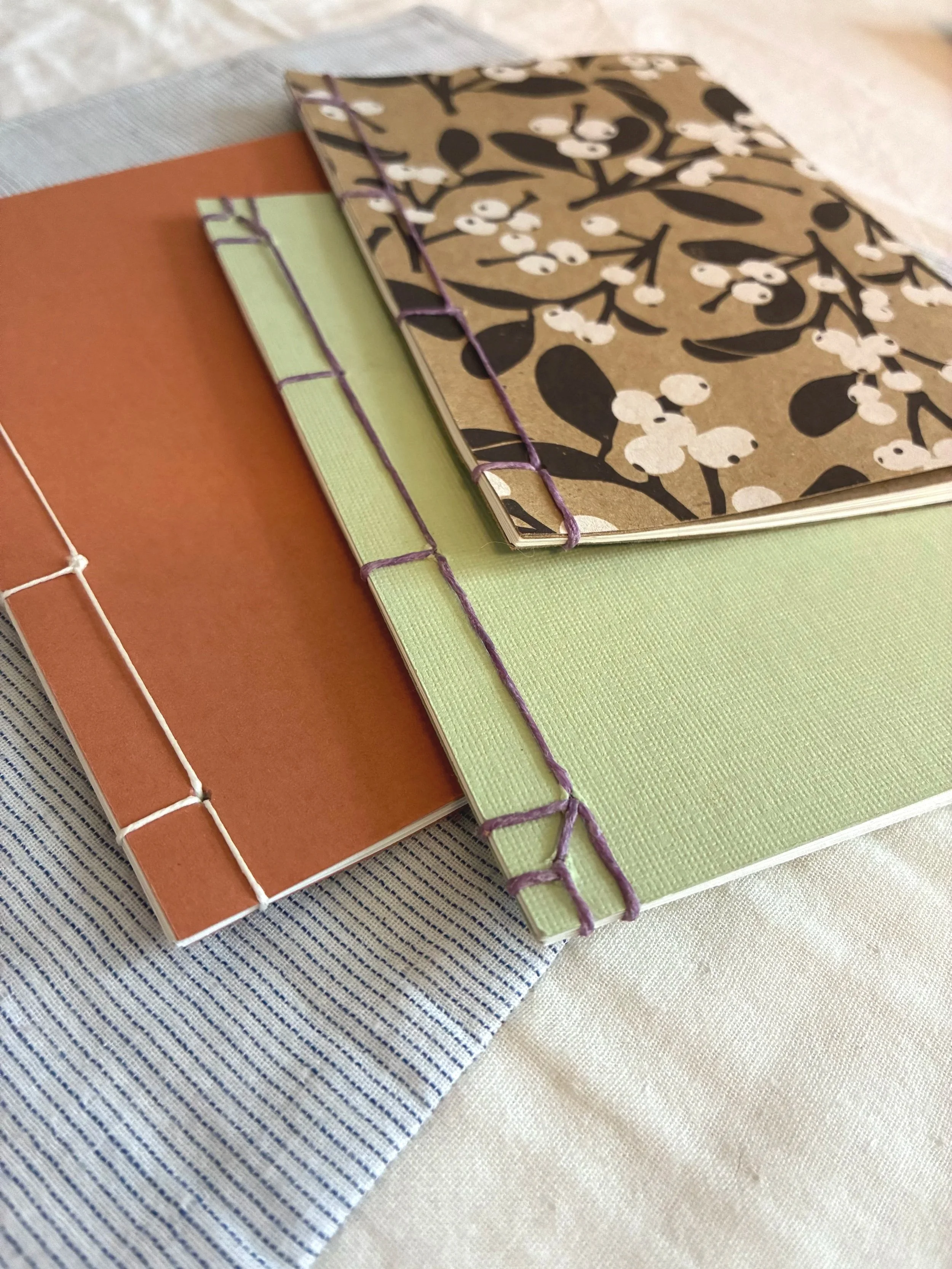 Close up image of three books hand bound in traditional Japanese binding style..