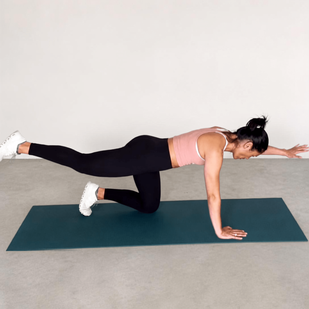 Woman doing the Bird Dog exercise on a teal mat, in a pink top and black leggings, showing core stability and balance.