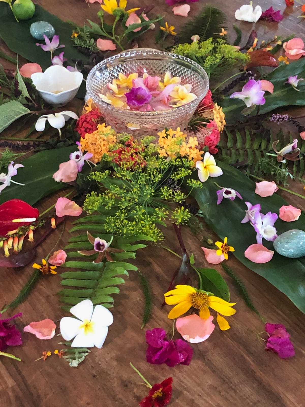 A decorative floral class centerpiece mandala with colorful flowers, petals, and leaves surrounding a glass bowl filled with flower petals to celebrate life and fertility for a Sacred Birth Class.  SacredBirthPath.com