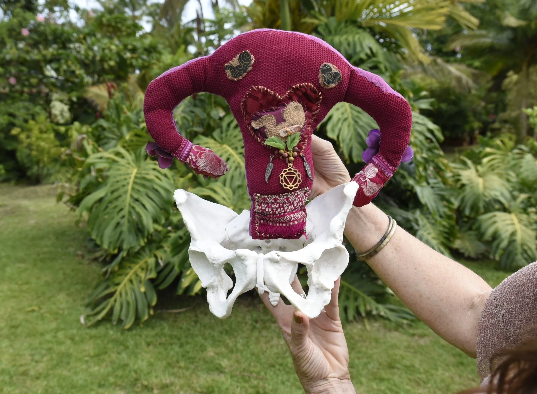Holding a handmade uterus inside a model of the pelvic bones to teach about womb wellness during a Sacred Birth Keepers training by Hope Medford -SacredBirthPath.com