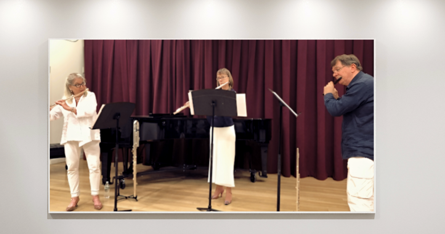Three musicians performing on stage with a grand piano and a maroon curtain backdrop.