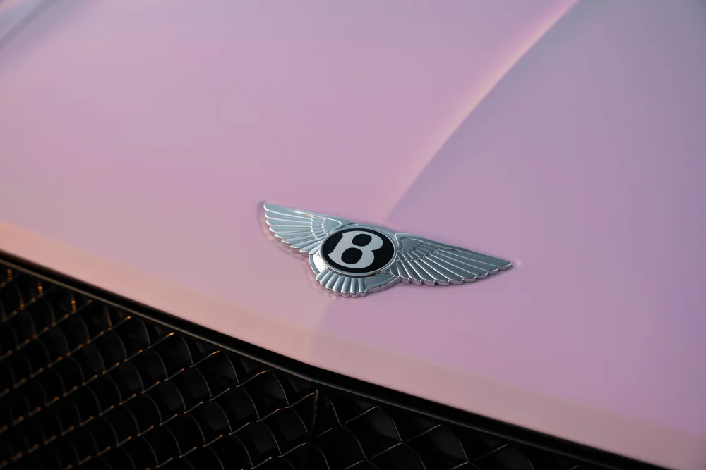 Winged Bentley badge on the pink Bentayga hood above the black mesh grille