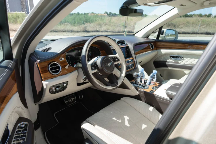 Cream-colored cabin with steering wheel, brown dashboard trim and an open front door.