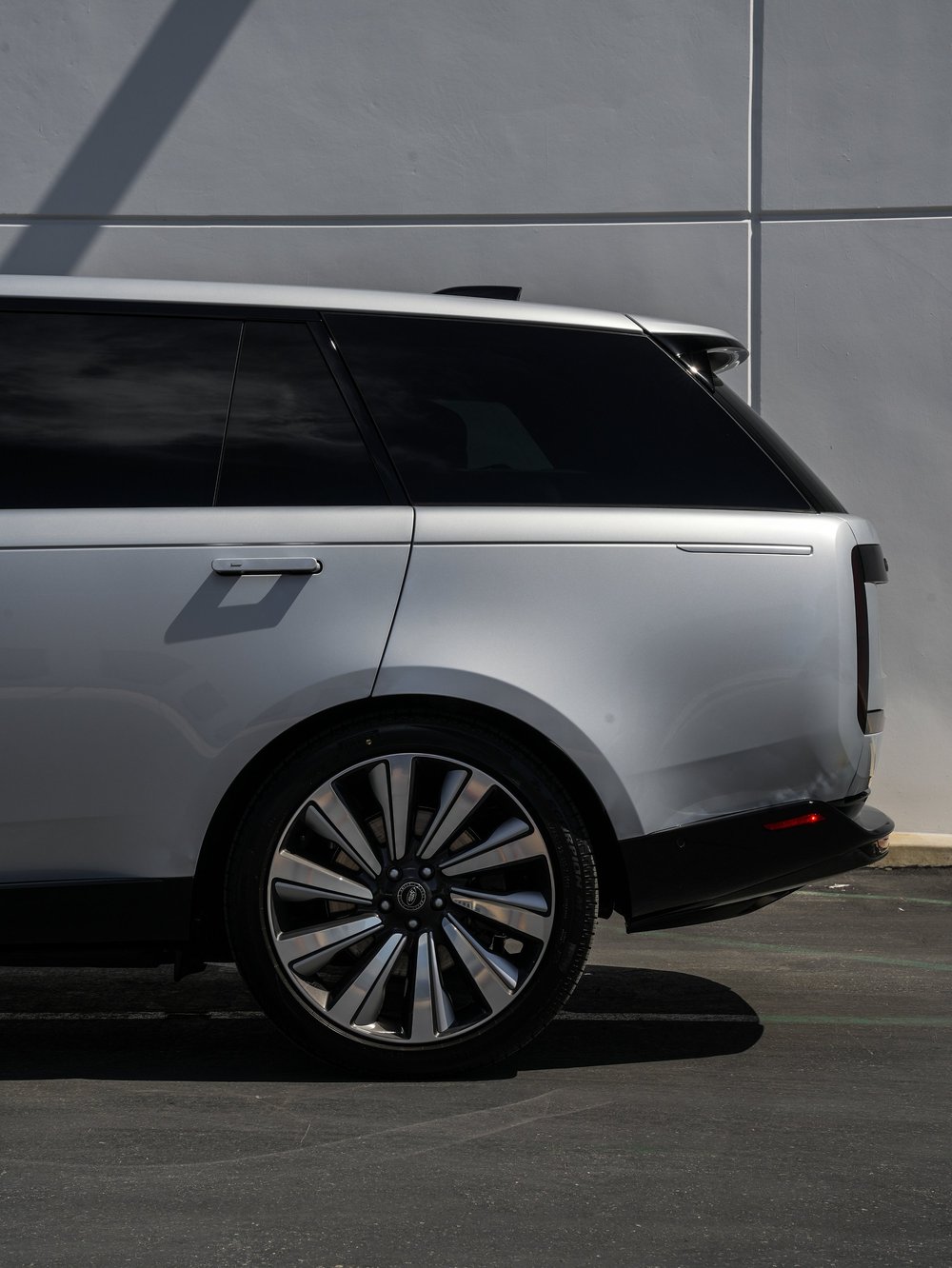 Rear-quarter detail of the silver Range Rover SV with its rear wheel and dark upper glass.
