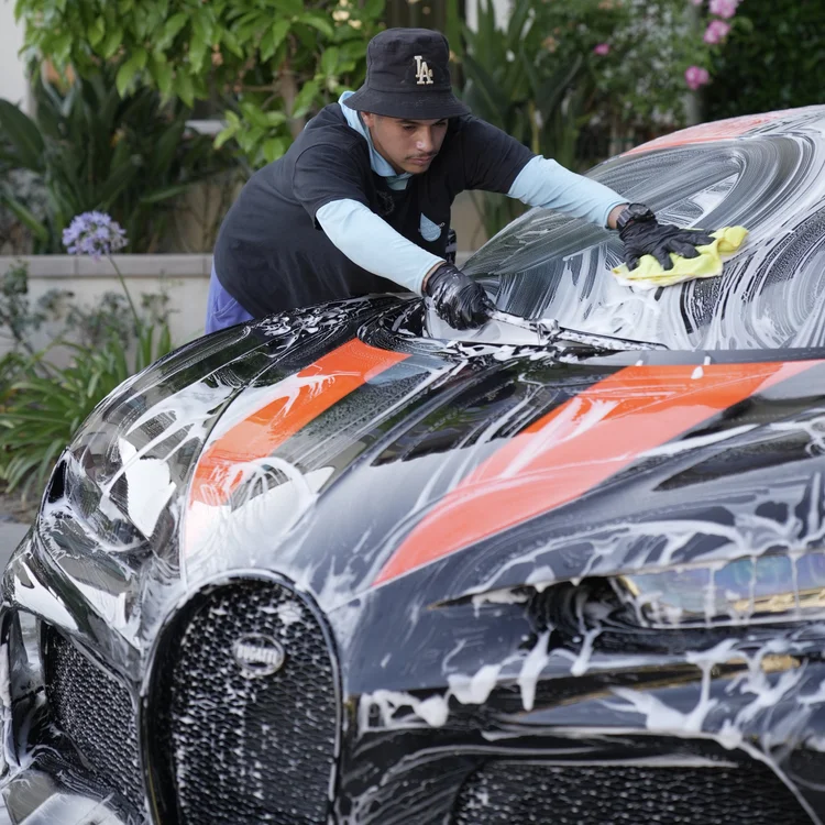 Toyz detailer hand-washing a performance vehicle with snow foam