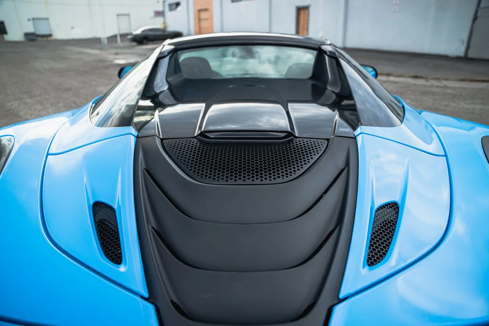 Elevated rear view of the blue 720S dark engine-cover louvers and mesh between the blue rear shoulders