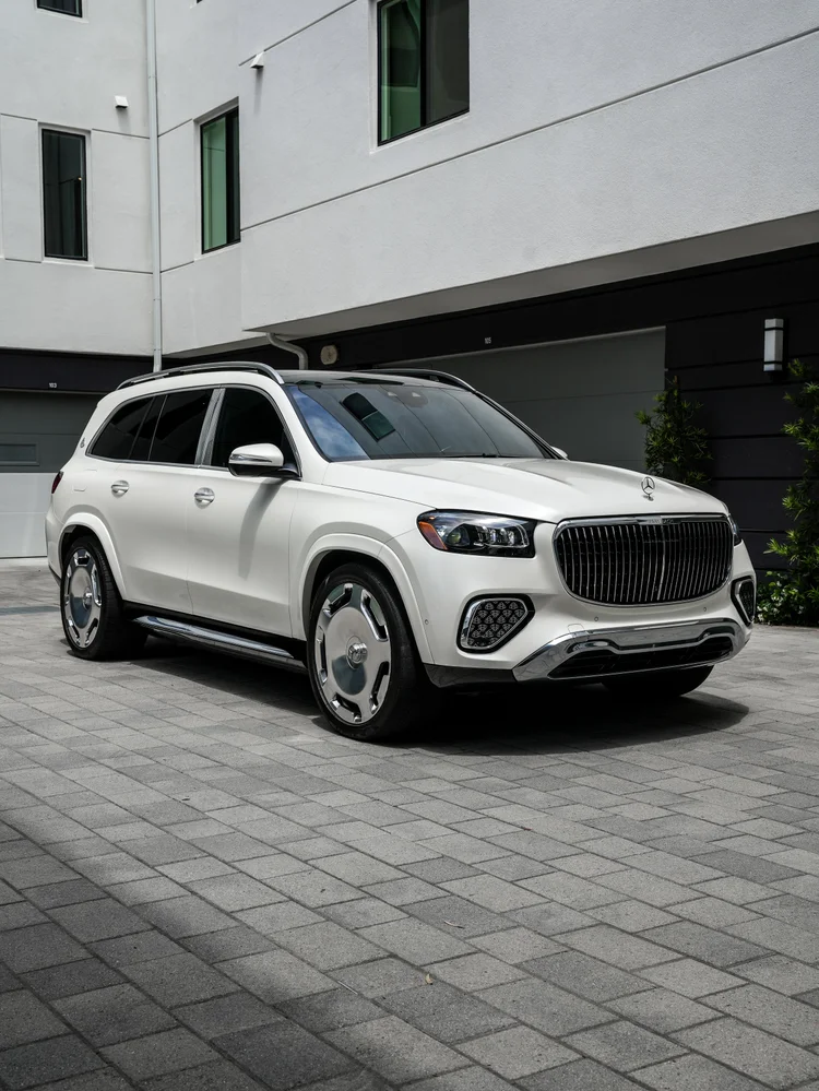 White Mercedes-Maybach GLS 600 in a complete front-three-quarter view with silver wheels outside a modern building