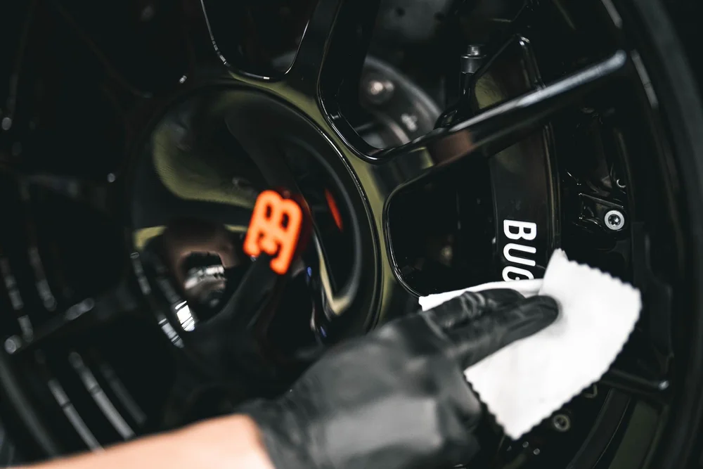 Technician applying surface protection to a performance vehicle wheel and caliper.