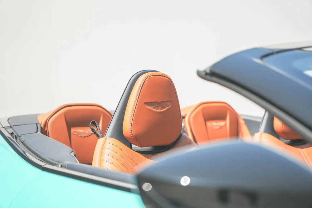 Orange DB11 front-seat headrest with winged embroidery, rear seats and blurred black mirror