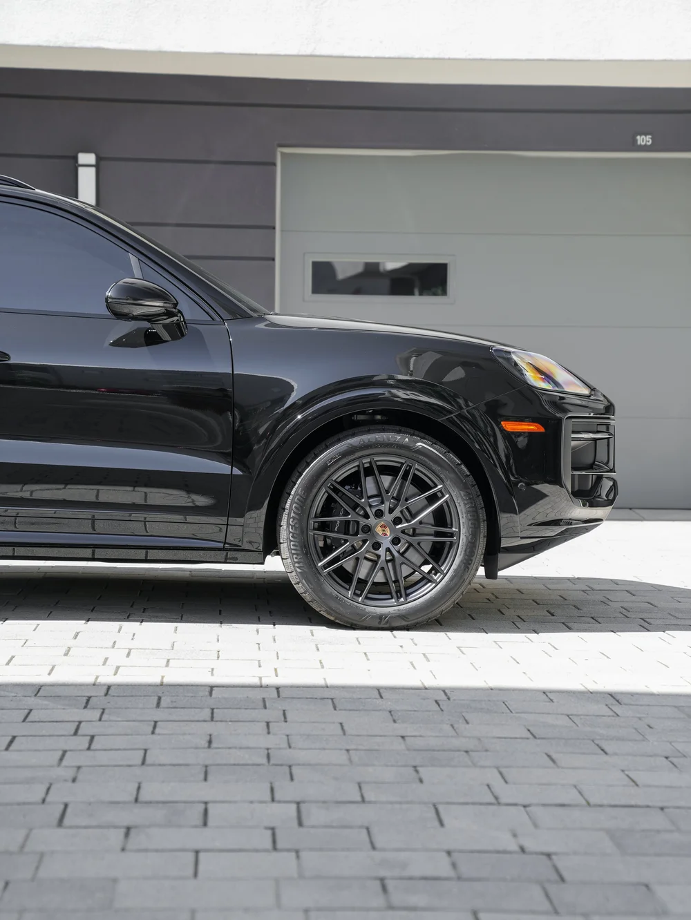 Side view of the black Cayenne GTS front wheel, fender, headlamp, mirror and front bumper.