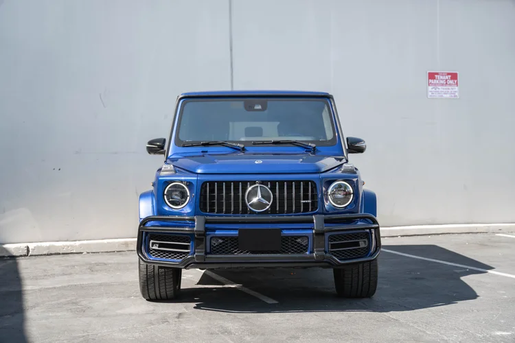 Complete straight front view of the blue G 63 with circular lamps, a vertical-bar grille and dark front guard