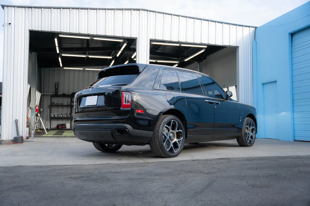 Rear three-quarter view showing the SUV's long side outside the open workshop bays.