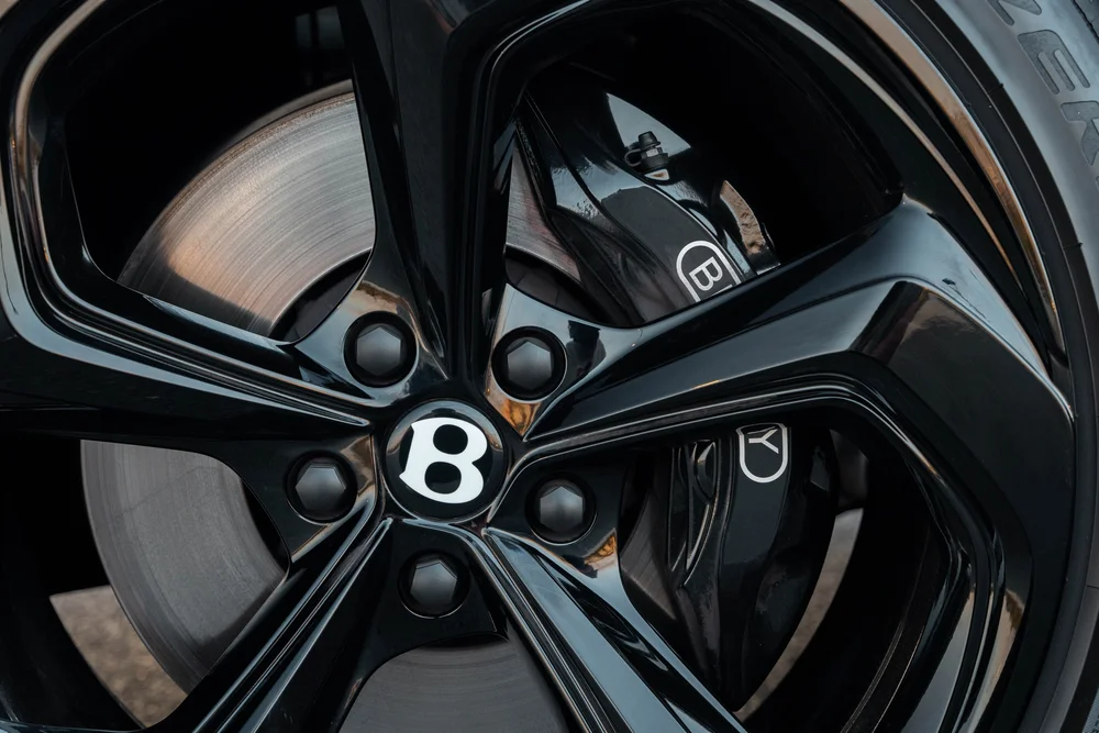 Close view of the Bentayga black wheel, Bentley center emblem, brake disc and dark brake caliper