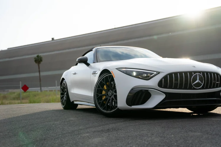 Close low front-three-quarter view of the white SL 63 showing the near wheel and yellow caliper with the nose cropped at right
