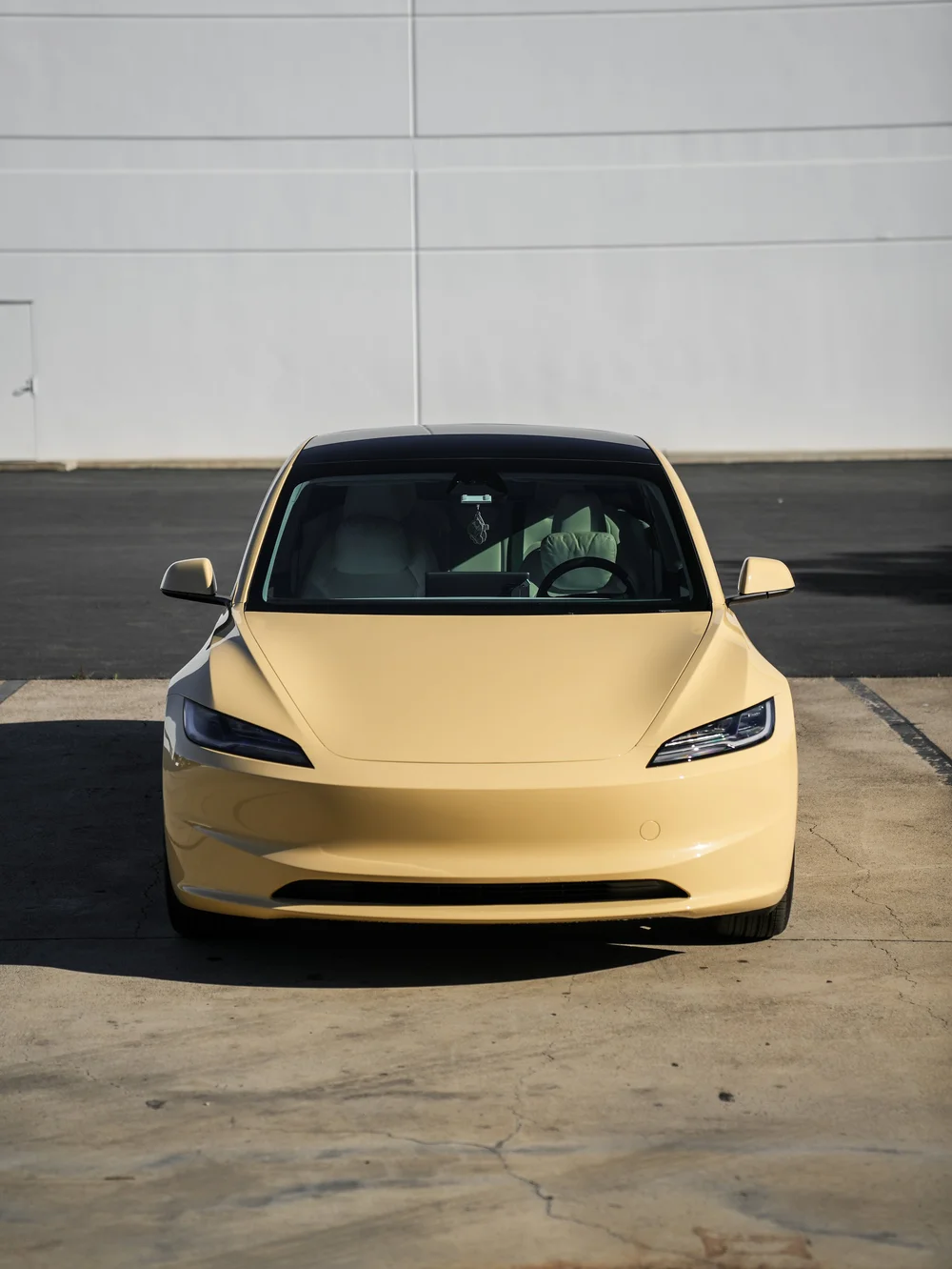 Tesla Model 3 in gloss Sunrise Yellow vinyl wrap, straight front view of the complete vehicle