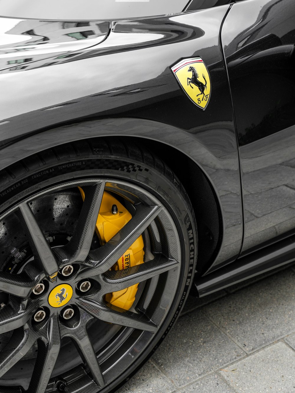Ferrari shield badge above the black front wheel and yellow brake caliper on the 296 GTB