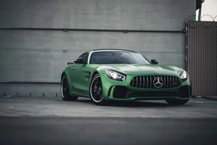 Green Mercedes-AMG GT R from the front three-quarter angle, with illuminated headlights, dark wheels and a black rear wing.
