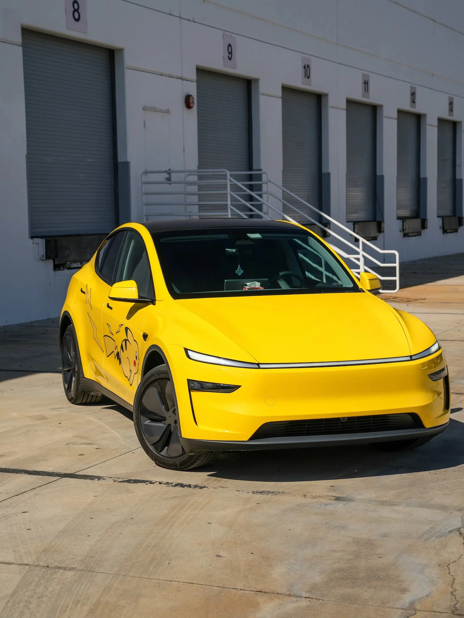 Tesla Model Y with Vegas Yellow vinyl wrap and Pikachu graphics, front three-quarter view