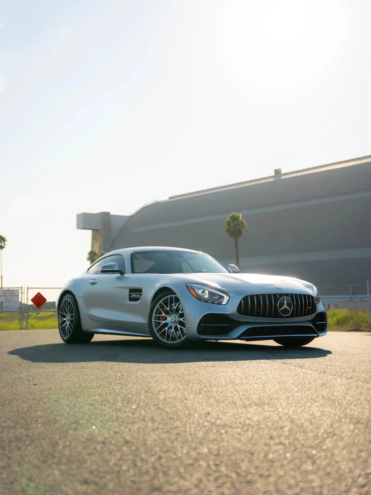 Silver Mercedes-AMG GT C in a complete front-three-quarter view outdoors with its roof and wheels in frame